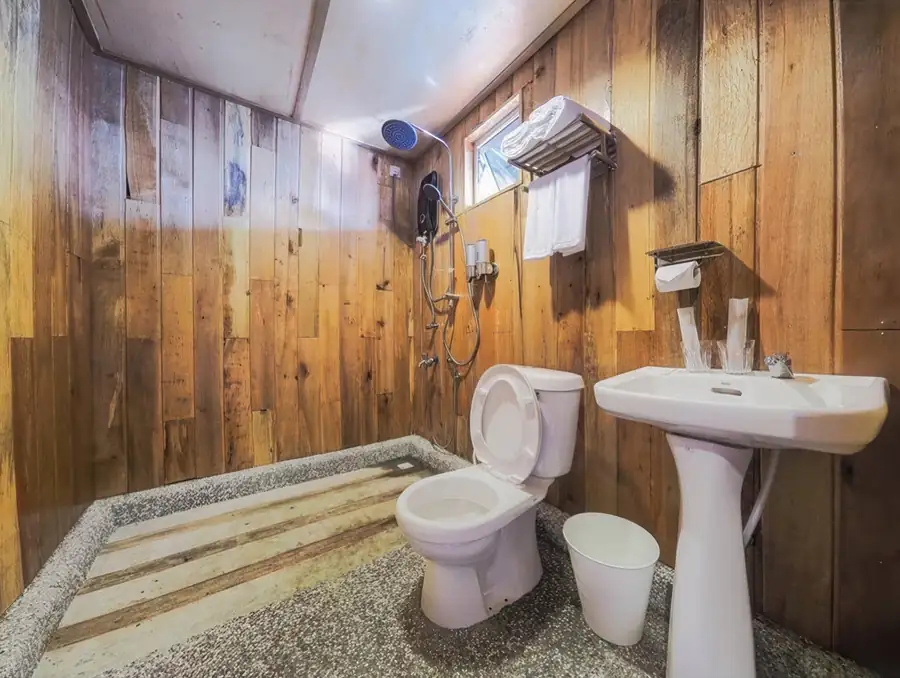 A nicely designed bathroom at Dreamy Wave Dwelling Resort highlighting modern grey tiled walls, a sleek washbasin with a square mirror, a white toilet, and a glass electric shower area.